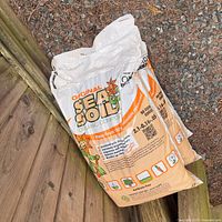 Three bags of Original Sea Soil organic compost placed on wooden steps outdoors.