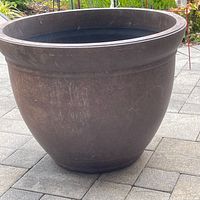 Photo of large round dark-colored garden planter with some surface wear.
