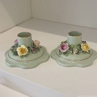 Two pastel green Adderley bone china candle holders with hand-painted three-dimensional flowers and gold trim.