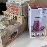 Boxes of Bernardin canning jars and new Kilner fermentation set on table.