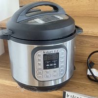 Front and side view of a stainless steel Instant Pot Duo electric pressure cooker with control panel visible on front.