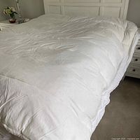 Full view of the white king size feather bed mattress cover on a bed.
