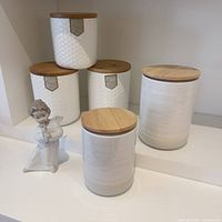 Overview of Lladró figurine with five ceramic canisters, showing texture and lids