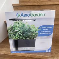 Box front showing AeroGarden In-Home Garden System with herbs growing under LED light.