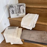 Additional linens including white towel, folded linen with grid pattern, and textured taupe fabric on stairs