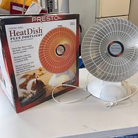 Presto HeatDish Plus Footlight parabolic space heater shown next to its original box with cat image and product features.