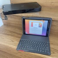 Samsung 3D Blu-ray player and Apple iPad with keyboard case on wooden surface