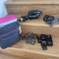 Full lot on wooden stairs showing the Sony Video8 Handycam camcorder, charger, batteries, wired remote, and black Lowepro carrying case.