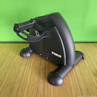 Side angle of black mini exercise pedal bike showing brand and base structure