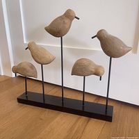 Full front view of the wooden birds mounted on a black base showing all five bird sculptures in a natural finish.