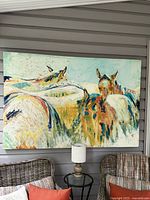 Abstract horse painting on canvas hung on a wall, accompanied by a small round table and two chairs with cushions.