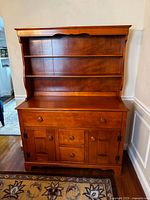 Front view of antique maple hutch showing shelves, drawers, and cabinets.