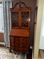 Full view of antique maple secretary desk with glass door cabinet, drawers, and slant front writing surface.