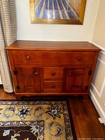 Front view of antique maple sideboard showing drawer and cabinet layout, wood finish and condition.
