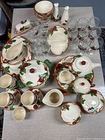 Top-down photo showing entire collection with apple motif dinnerware and glassware on table.