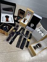 Image showing eleven men's wristwatches from various brands including boxes from Titan, Gruen, and Fossil. Watches have mixed leather and metal bands and various dial designs.