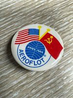 Close-up image of a small round vintage pin featuring Pan Am and Aeroflot logos with American and Soviet flags.