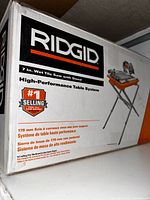 Photo of original packaging box of RIDGID 7-inch Wet Tile Saw with Stand showing brand, model, blade size, and features.