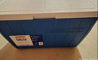 Front view of a blue and white Coleman Chiller cooler with label on the front indicating 21 quart capacity.
