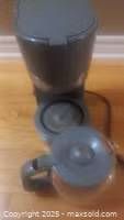 Photo of gray drip coffee maker with glass carafe, showing top and side views.