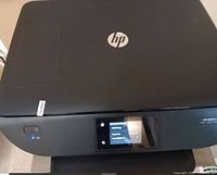 Closed view of HP ENVY 5640 printer showing top and front with hp logo and power button illuminated.