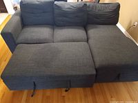 Photo of the dark gray sectional couch with three back cushions and chaise lounge showing the overall couch structure and fabric texture.