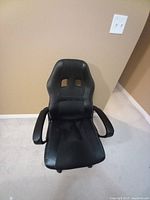 Front view of black ergonomic office chair with padded seat and backrest, armrests, and cutout design on upper back support.