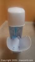 White plastic diaper pail with lid open, showing the internal compartment and blue odor control insert.