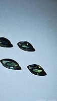 Four natural marquis cut sapphires laid flat showing blue and green colors with high luster on white background.