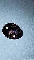 Oval cut faceted sapphire showing deep purple hue under natural or neutral light.
