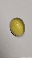 Close-up of a smooth oval cabochon lemon citrine gemstone on a white background.