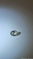 Oval cut light green sapphire with slight off white green color photographed on a white background to capture color and clarity visible from multiple angles.