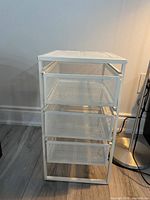 Full view of the white metal mesh storage cabinet showing all three pull-out drawers and top surface.