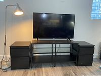 Full view of the TV stand, two side tables, and TV placed on stand showing arrangement and overall condition.