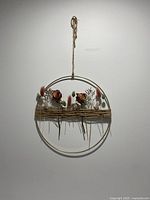 Front view of circular metal hoop decorated with dried flowers and wrapped jute twine.