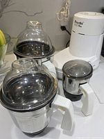 Photo showing Preethi ECO Plus electric mixer grinder base and three stainless steel jars of various sizes with lids.