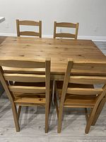Dining table set with 4 ladder-back chairs viewed from above and behind showing wood grain and knots.