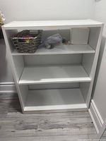 Frontal view of the white wooden 3-tier storage shelf showing minor surface wear and no accessories.