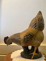 Side view of chicken figurine showing detailed feathers and yellow claws