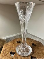 Side view of a clear crystal vase showing etched cut patterns on the body and flared neck.