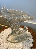 Clear glass boot-shaped cornucopia vase with raised hobnail dots and ruffled opalescent rim, side view.