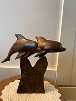 Front view of heavy ironwood dolphin sculpture showing two dolphins on wooden base.