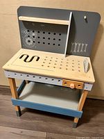 Front view of wooden kids toy workbench with pegboard and cutout work surface, showing condition and broken corner