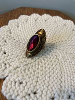 Close up front view of the purple faceted glass ring with brass decorative bezel and copper color showing through.