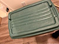Top view of the Rubbermaid storage container with hinged lid showing surface scratches and handle areas.
