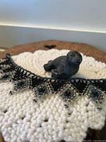 Photo showing the seal figurine and the beaded ankle bracelet resting on a white textured knit surface with a brown background.
