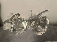 Two clear glass candleholders shaped as sitting bunnies, shown side by side.