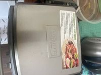 Photo showing the top and part of the side of the Cuisinart stainless steel grill closed, with logo and label visible on lid.