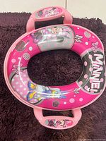 Photo of pink Disney Minnie Mouse themed plastic child potty seat with handles on a dark surface