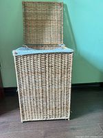 Side view of large rectangular bamboo wicker laundry basket with lid open showing fabric lining inside.
